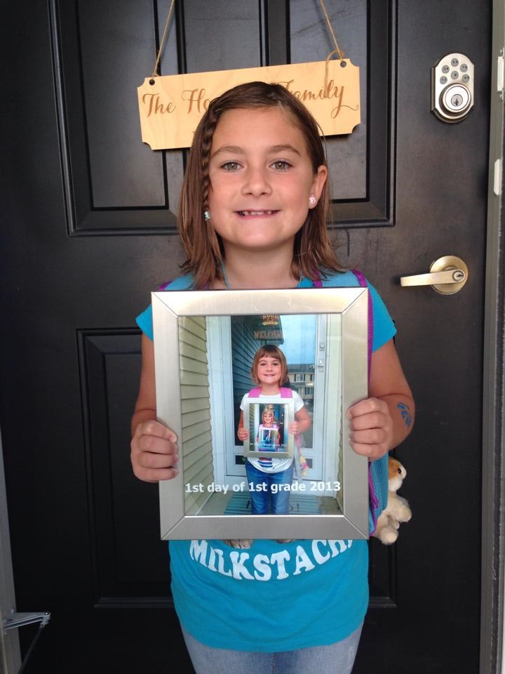 Mulai 2nd grade by holding a pic of what she looked like starting 1st grade.