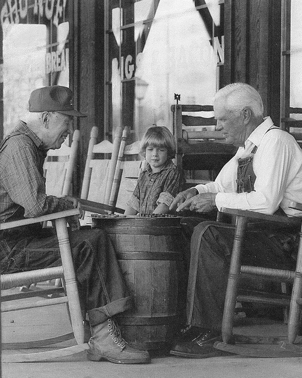 가족 gathered around an old cracker barrel.