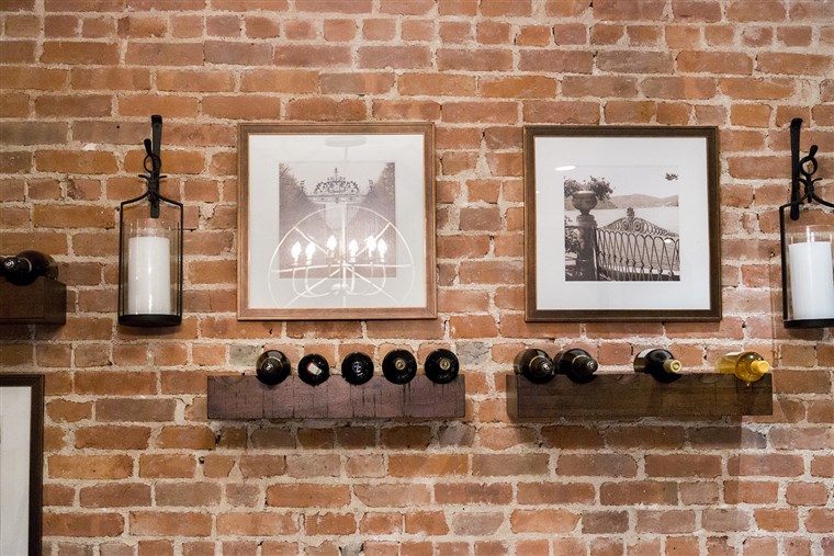 ディラン and her husband decided to store their wine bottles by creating a wine display on an exposed brick wall near the kitchen.