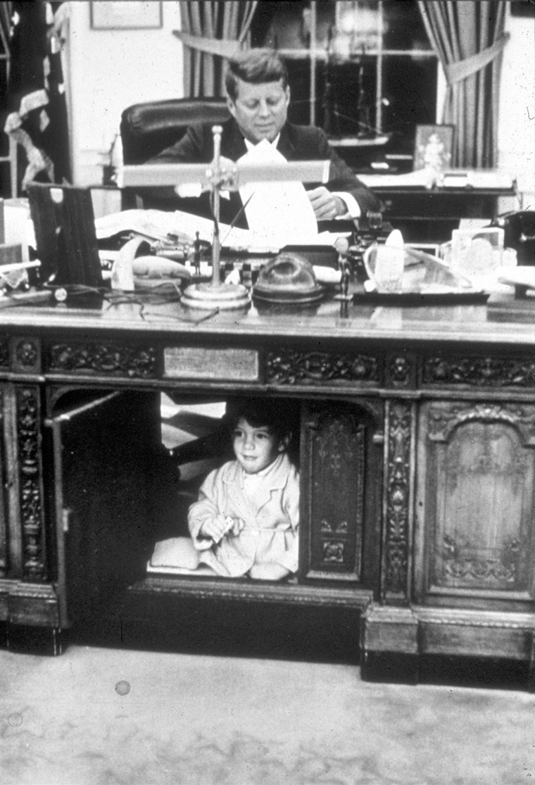 John F. Kennedy Jr. hides in his father's Oval Office desk in October 1963.