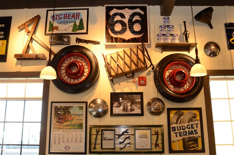 역사적인 decorations pay homage to California's Route 66, such as an antique tire, luggage rack and suitcase, old motor oil cans, and an antique Esso calendar from June 1969.