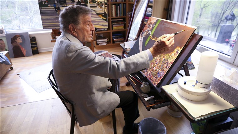에서 his New York art studio, Tony Bennett finishes a painting while sitting among several of his completed works. 