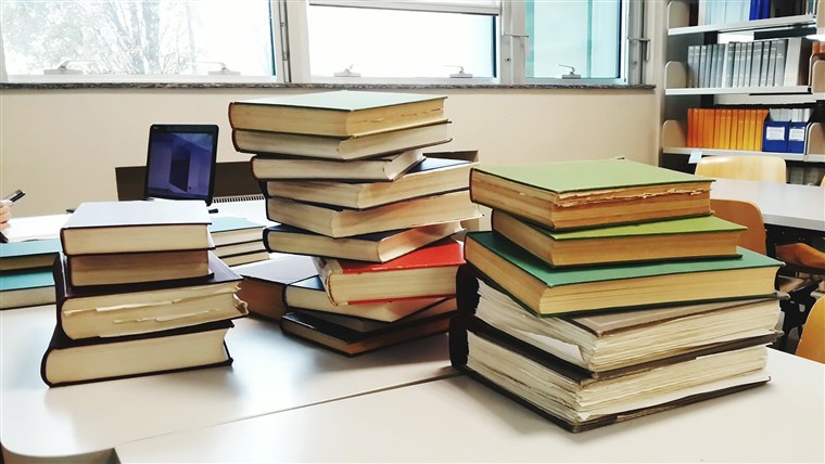 画像： Close-Up Of Hardcover Book Stacks On Table In Library