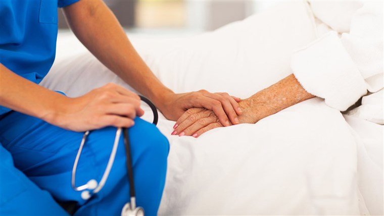 Infermiera holds elderly patient's hand