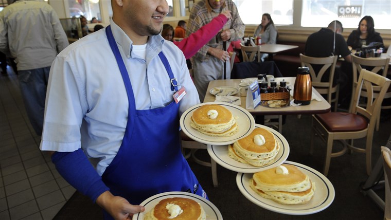 サーバ Ruben Avalos performs a balancing act with several plates of the free pancakes.