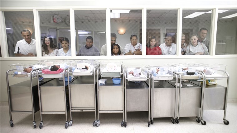새로운 parents watching babies in hospital nursery