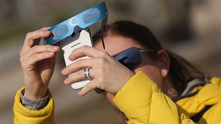 UN woman uses special glasses and a smartphone to photograph eclipse