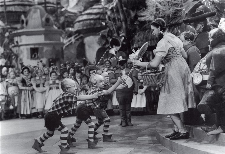 Jerry Maren presents Judy Garland with a lollipop in the film 'The Wizard of Oz.'