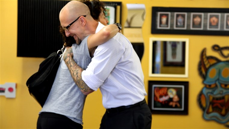 Tatoo artist Trent Wyczawski hugs nipple tattoo client Adrienne Peres