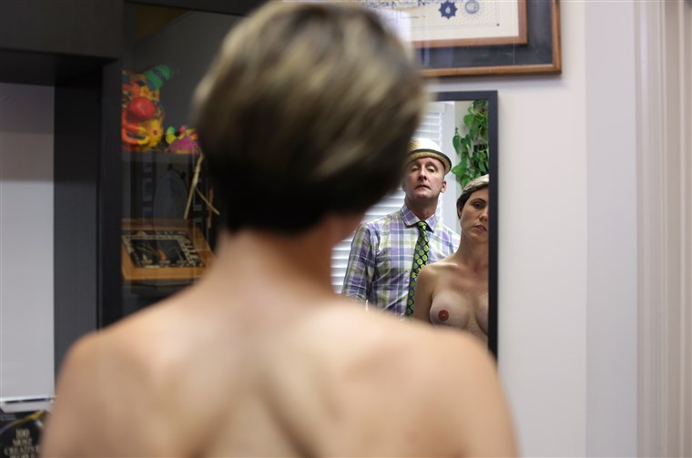 Capezzolo tattoo artist Vinnie Myers examines a breast cancer survivor
