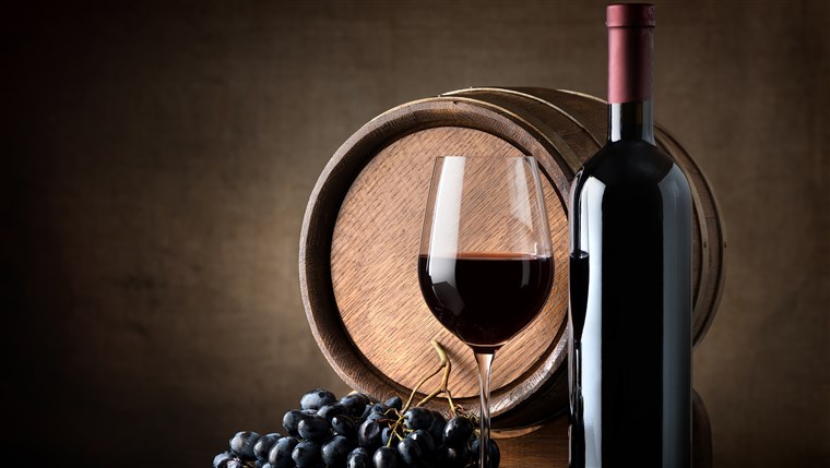 병 of red wine, grapes and wooden barrel