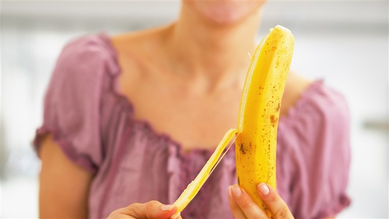Avvicinamento on young woman peeling banana