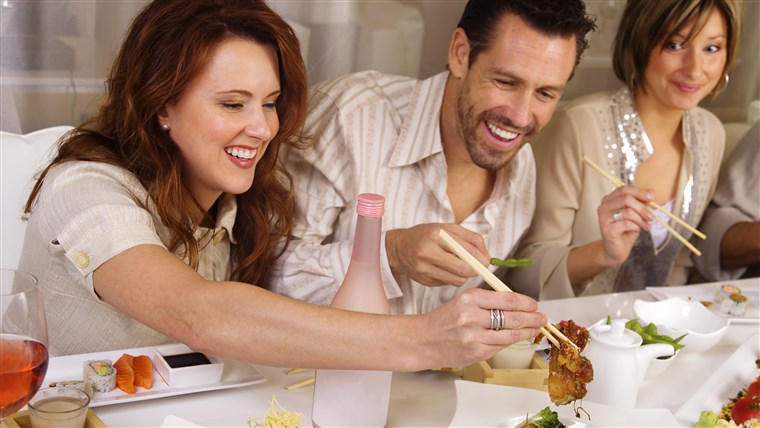 グループ of attractive people eating and socializing at a restaurant