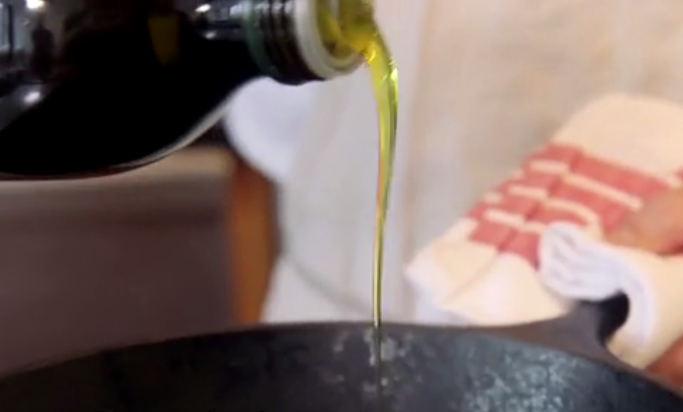 Menuangkan olive oil into pan