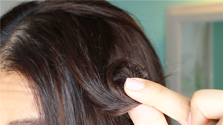 Membuat pin curls by winding 2-inch sections of hair around your finger.