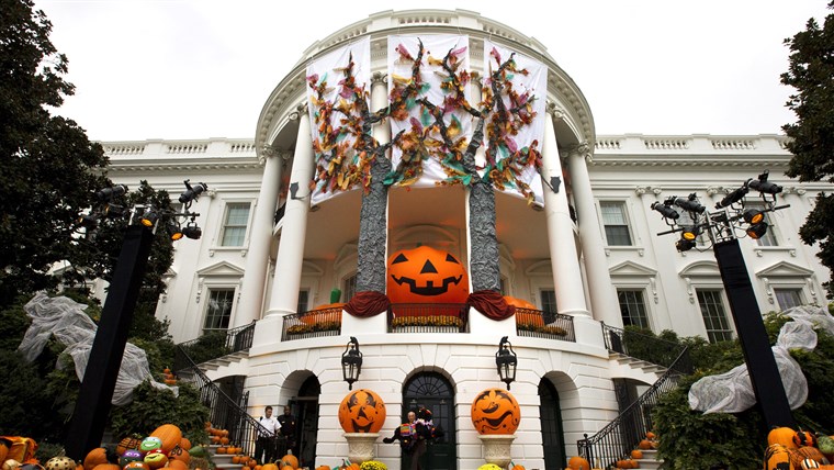 UN White House usher takes a model of one of the Obama dogs outside as Halloween decorations adorn the South Portico of the White House in Washington, ...