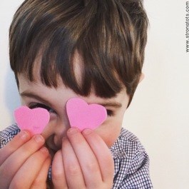 소년 holding hearts up in front of his face